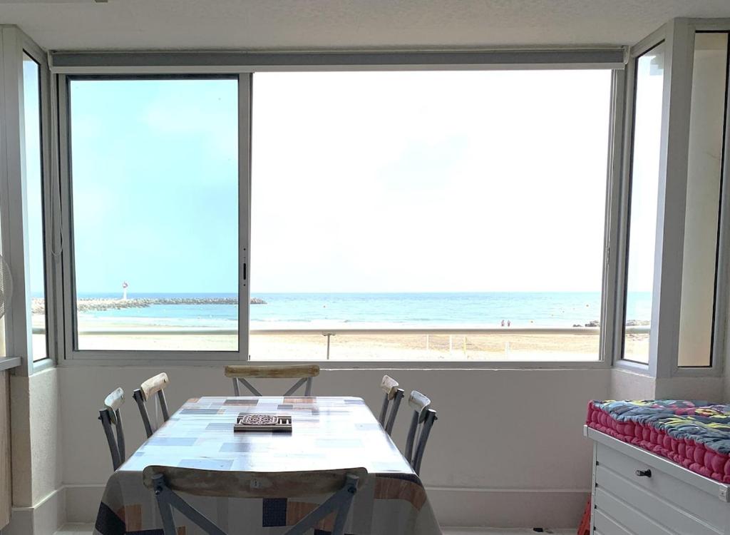 une salle à manger avec une table et une vue sur la plage dans l'établissement Appartement lumineux en front de mer, à Frontignan