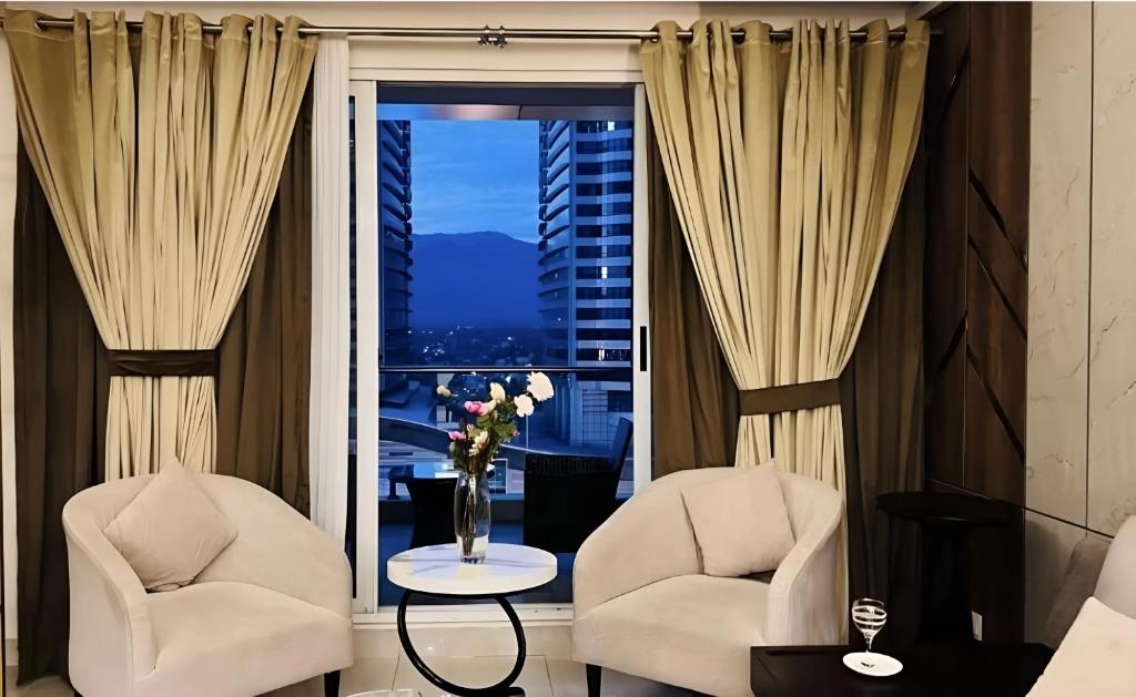 a living room with two chairs and a window at Skyline Premium Luxury Apartments Elysium Facing Centaurus Mall Islamabad - LMY in Islamabad