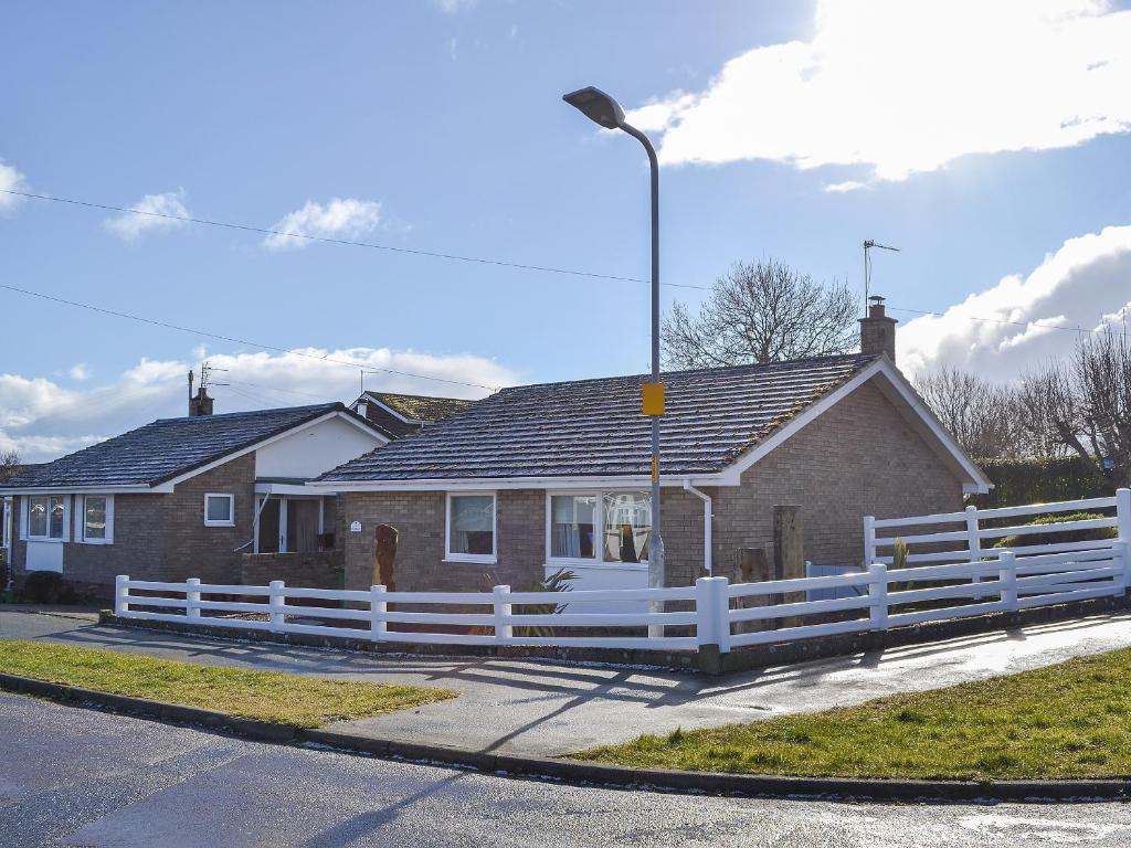 a house with a white fence in front of it at Fairways in Beadnell