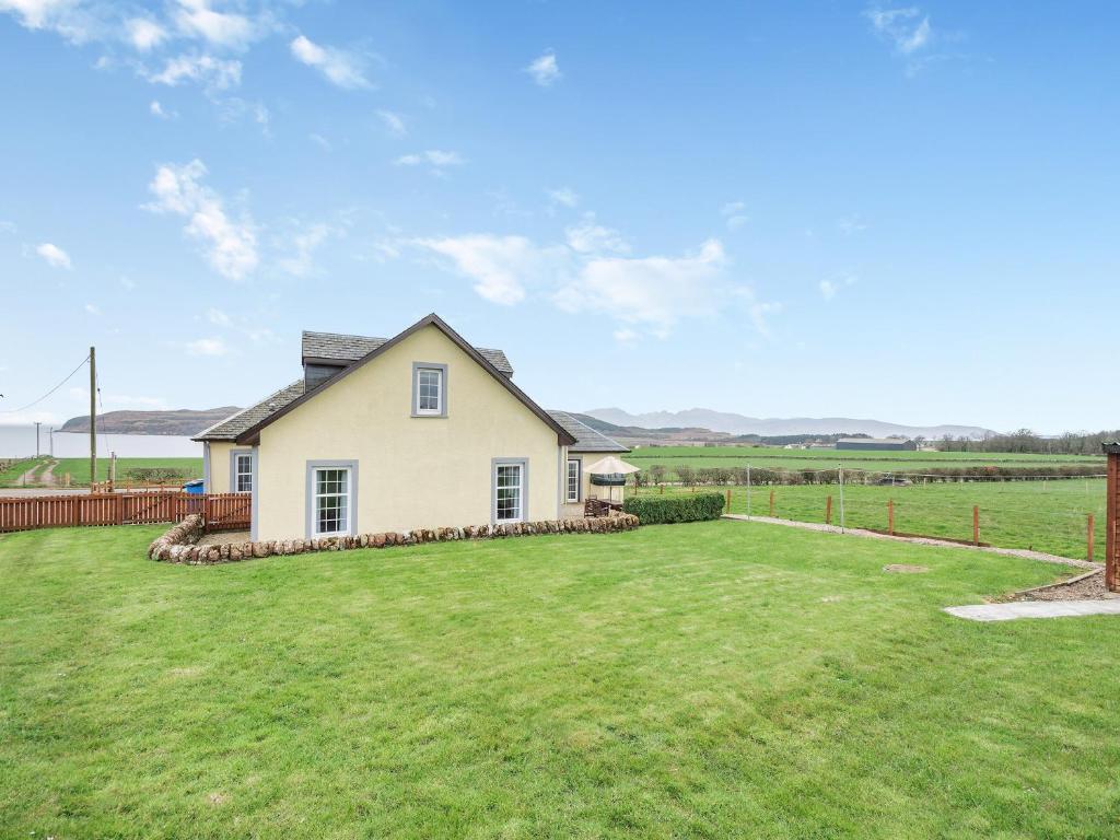 a white house with a large grass yard at Kerrytonlia Cottage in Mountstuart