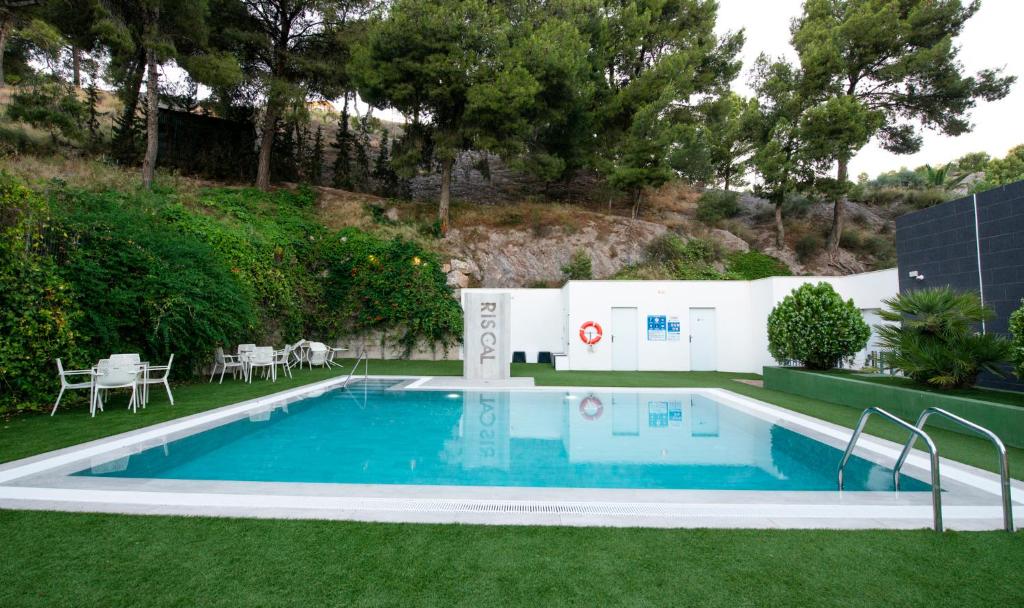 a swimming pool in a yard with grass and trees at Sercotel Riscal in Puerto Lumbreras