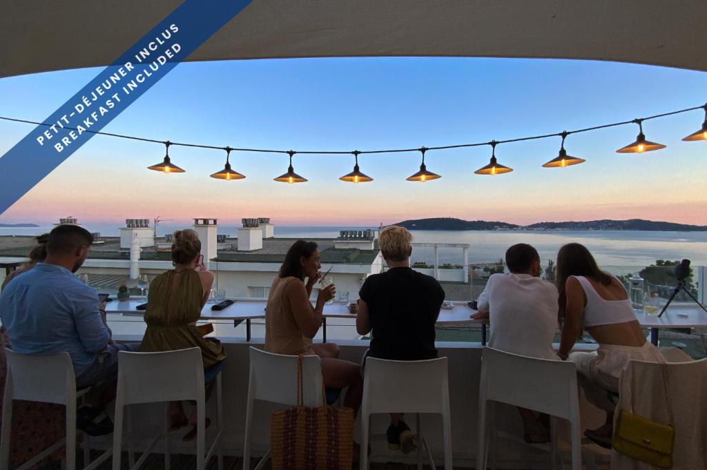 a group of people sitting at a table watching the sunset at Hôtel Les Voiles in Toulon