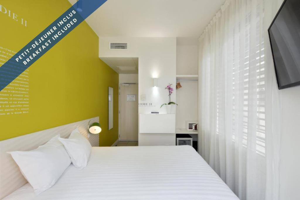 a bedroom with a white bed and a television at Hôtel Les Voiles in Toulon