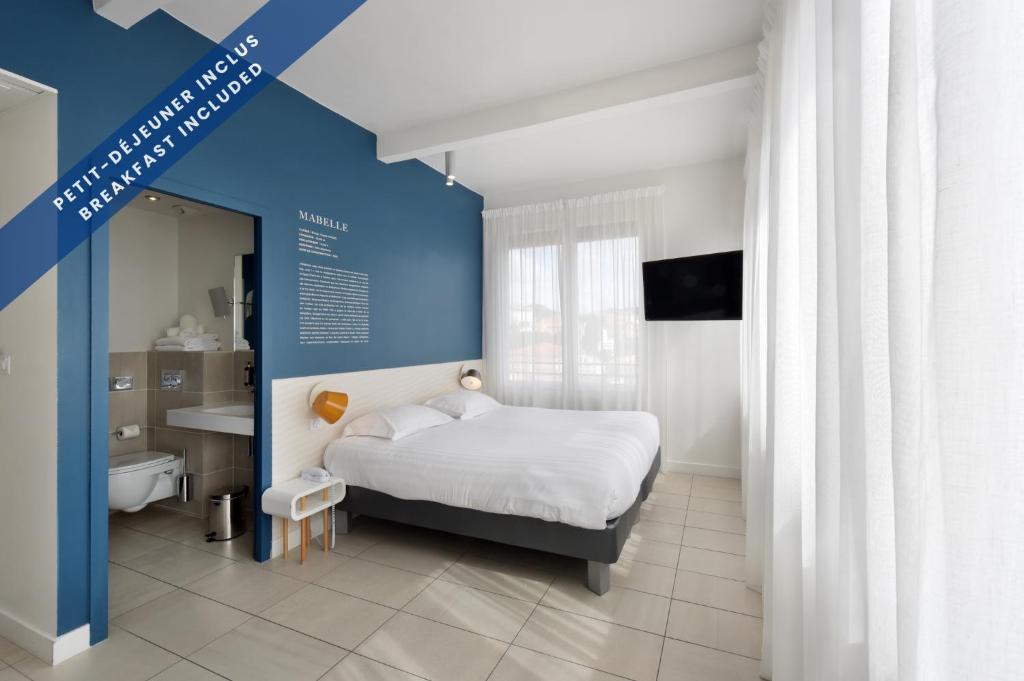 a bedroom with a bed and a bathroom with a sink at Hôtel Les Voiles in Toulon