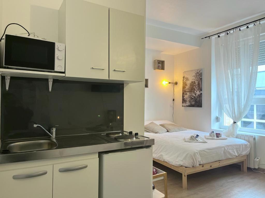 - une cuisine avec évier et un lit dans une chambre dans l'établissement Marguerite6 cosy & tout équipé proche centre ville, à Reims