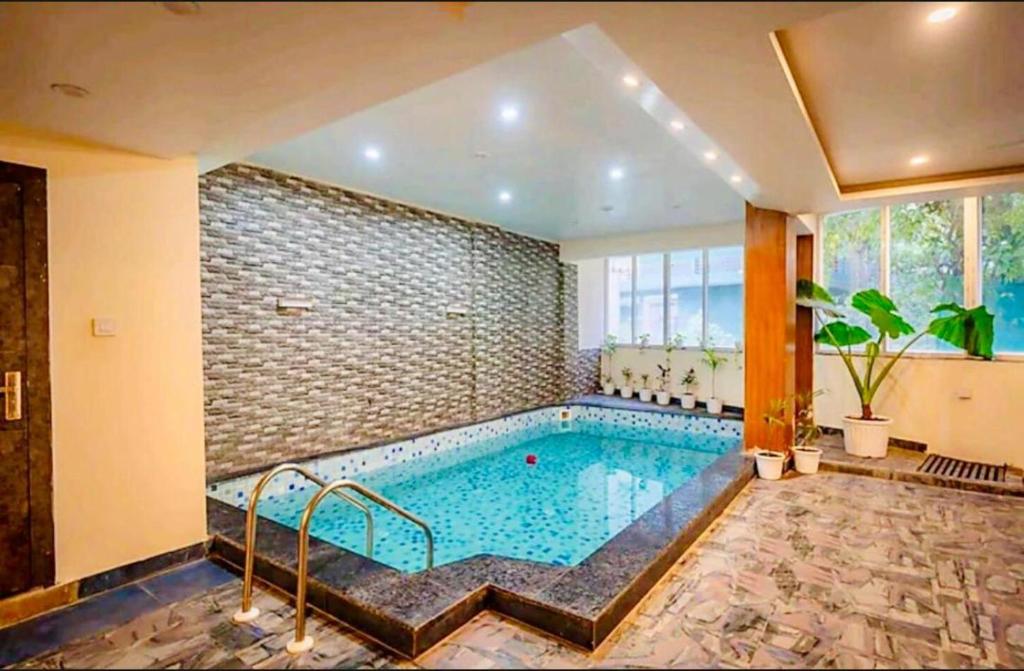 una piscina en una habitación con una pared de ladrillo en The Shore Travelista, en Rishīkesh