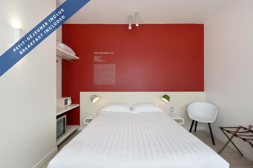 a bedroom with a white bed and a red wall at Hôtel Les Voiles in Toulon