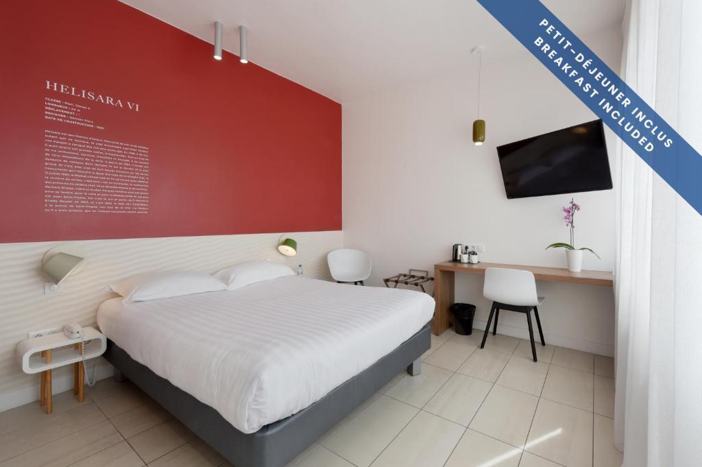 a bedroom with a bed and a desk and a tv at Hôtel Les Voiles in Toulon
