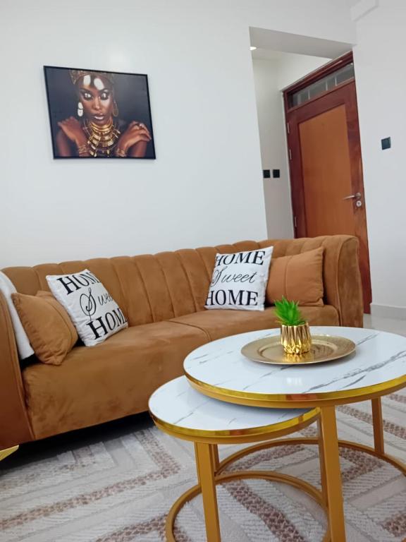 a living room with a brown couch and a table at Belaire Bnb one bedroom in Thindigua kiambu road in Kiambu