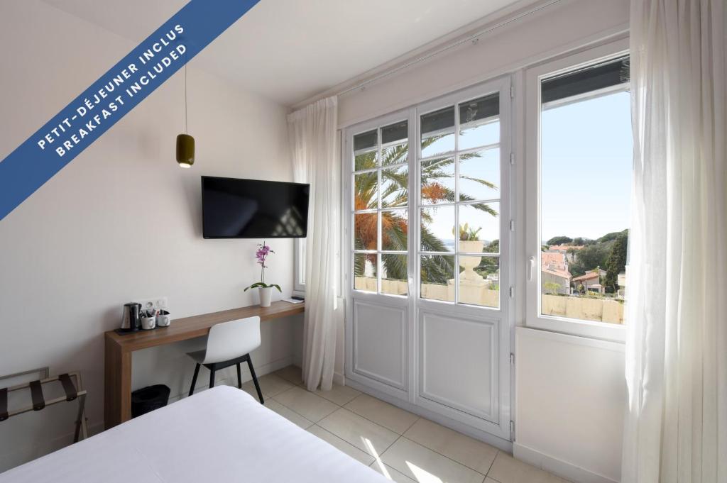 a bedroom with a bed and a desk and a window at Hôtel Les Voiles in Toulon