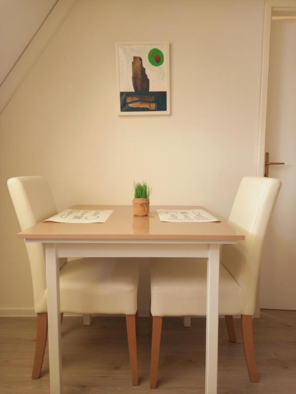 a dining room table with two white chairs at Ena Apartment in Tuzla