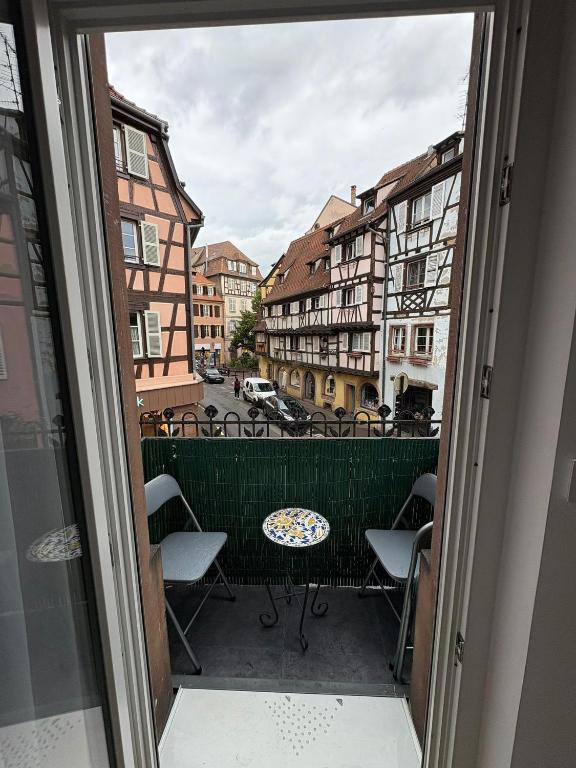- un balcon avec des chaises, une table et des bâtiments dans l'établissement Nouveau! Appartement spacieux en Hypercentre, à Colmar
