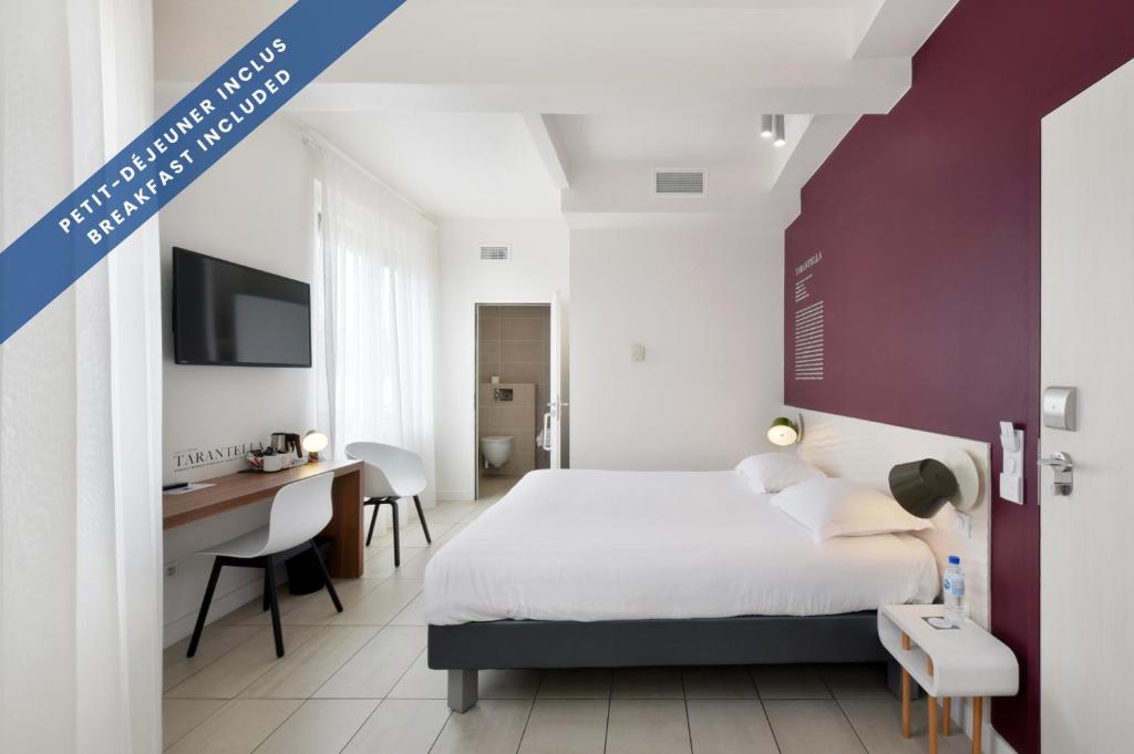a bedroom with a bed and a desk and a tv at Hôtel Les Voiles in Toulon