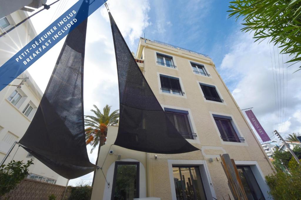 a building with two large black sails in front of it at Hôtel Les Voiles in Toulon