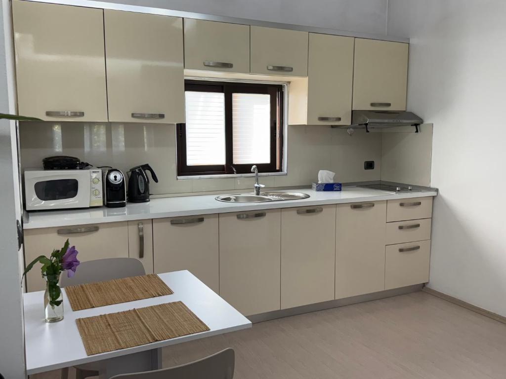 a kitchen with white cabinets and a table and a microwave at Ani Apartment with Fireplace in Tirana