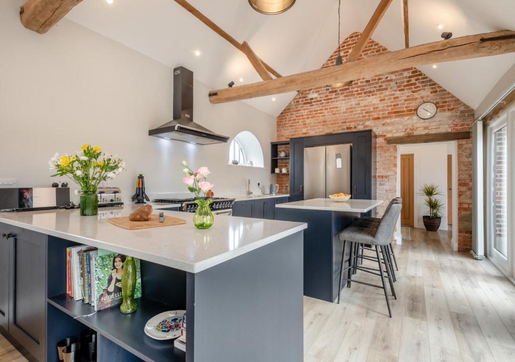 une cuisine avec des placards bleus et un mur en briques dans l'établissement Iken Barn, à Neatishead