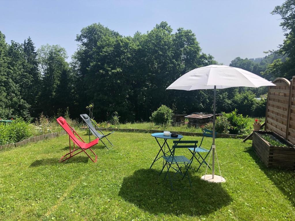- deux chaises et une table avec un parasol dans la cour dans l'établissement Independent studio in a chalet, à Mont-Saxonnex