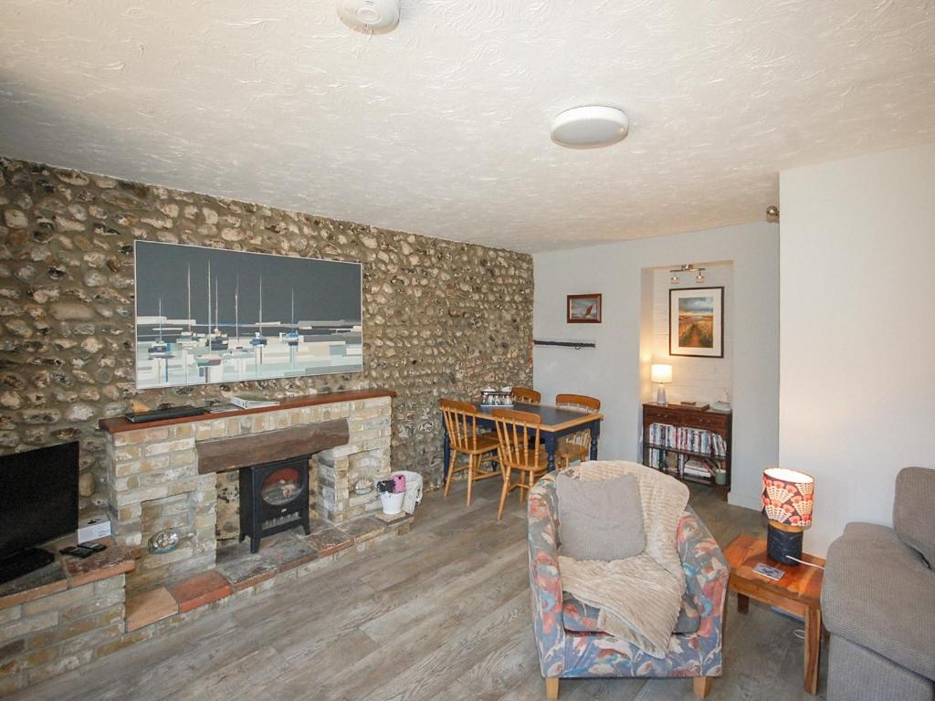 a living room with a fireplace and a tv on a stone wall at Wherry Cottage in Wells next the Sea