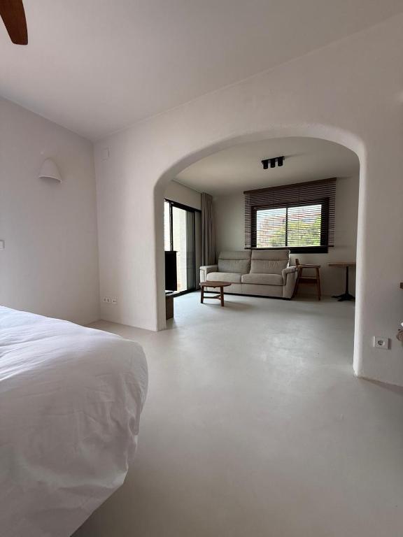 a white bedroom with a bed and a couch at Casa Bel - Apartment 5 in Miami Platja