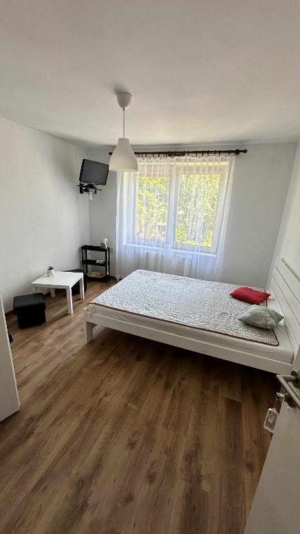 a bedroom with a bed in a room with wooden floors at na rogu in Pobierowo