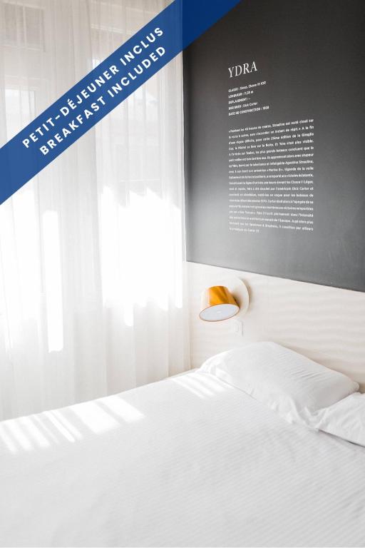 a bedroom with a white bed and a window at Hôtel Les Voiles in Toulon