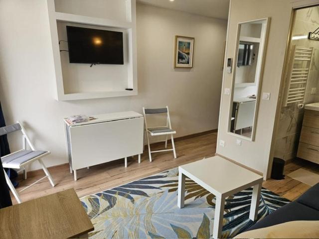 a living room with a tv and a table and chairs at Elegant studio, 2-4 people, WiFi, pool, parking in Biarritz