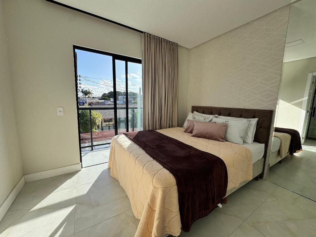 een slaapkamer met een groot bed en een groot raam bij Casa Nova - Moderna | 700m praia | 8 min parque in São Lídio