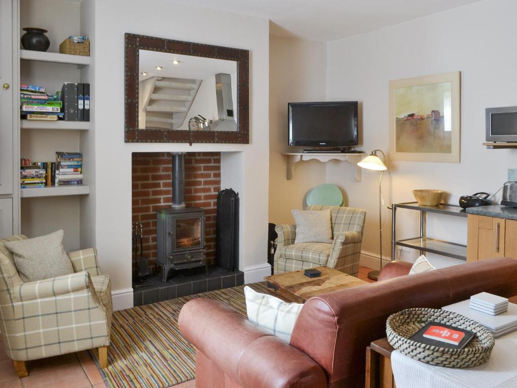Una sala de estar con un sofá y una chimenea. en Youngers Cottage, en Warkworth