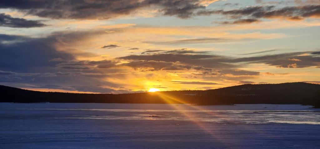 a sunset over a lake with the sun setting at Smedjan in Mellanström