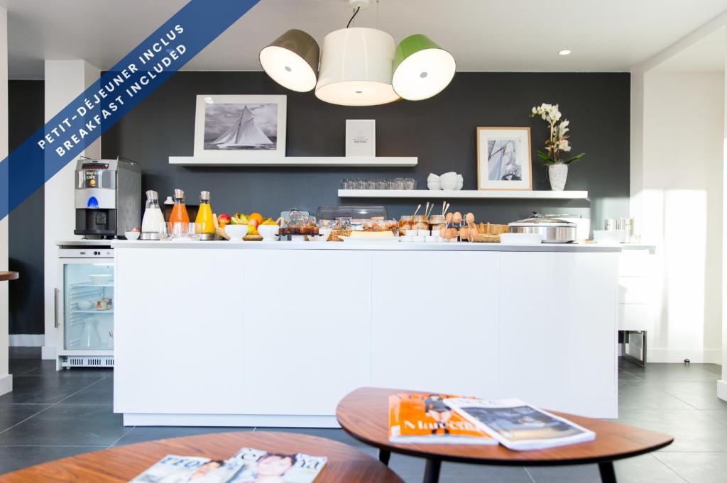 a kitchen with a white counter and a table at Hôtel Les Voiles in Toulon