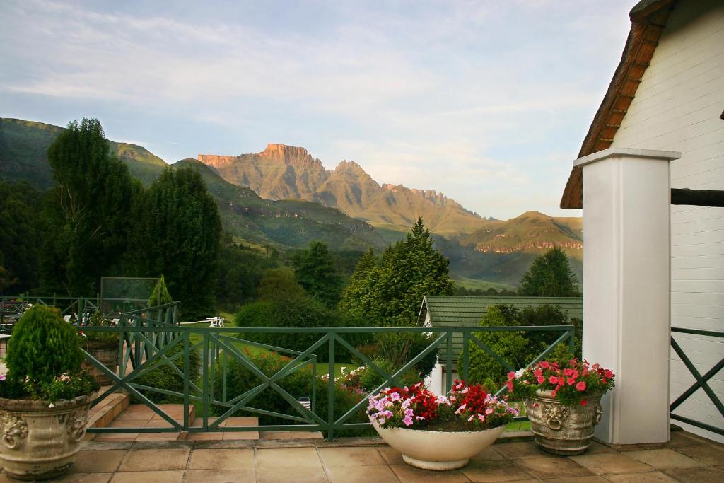 a balcony with two pots of flowers and mountains at Champagne Castle Hotel in Champagne Valley