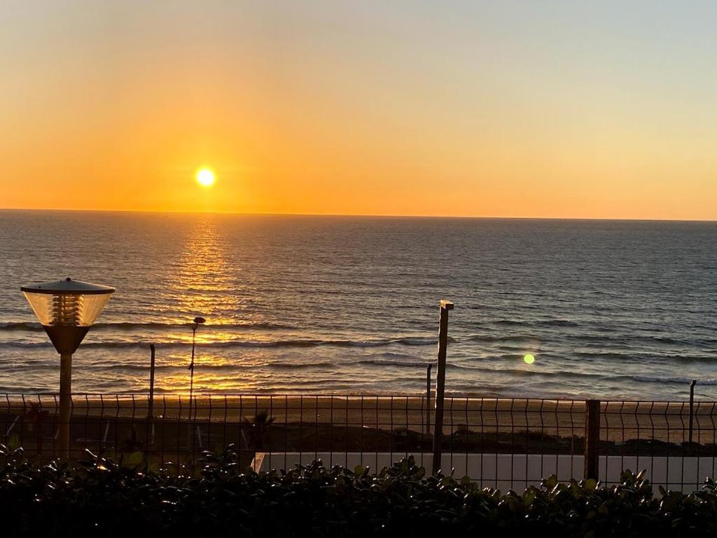 a sunset over the ocean with a street light at Appartement à Prestigia Plage des nations salé in Sale