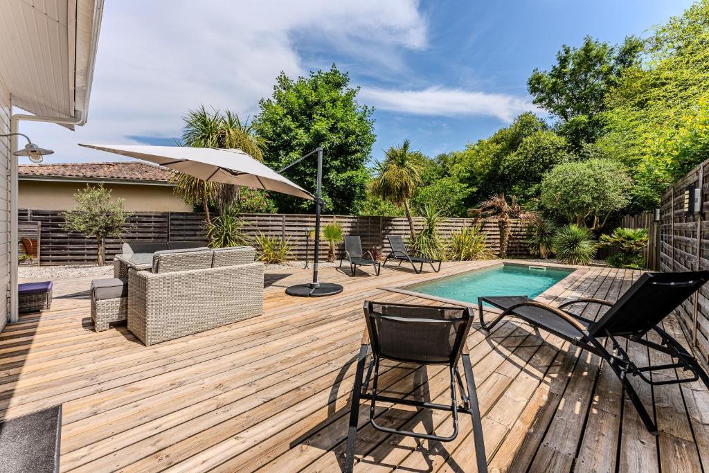 une terrasse en bois avec des chaises et une piscine dans l'établissement Pretty house with pool and large terrace - Bassin d'Arcachon, à Arès
