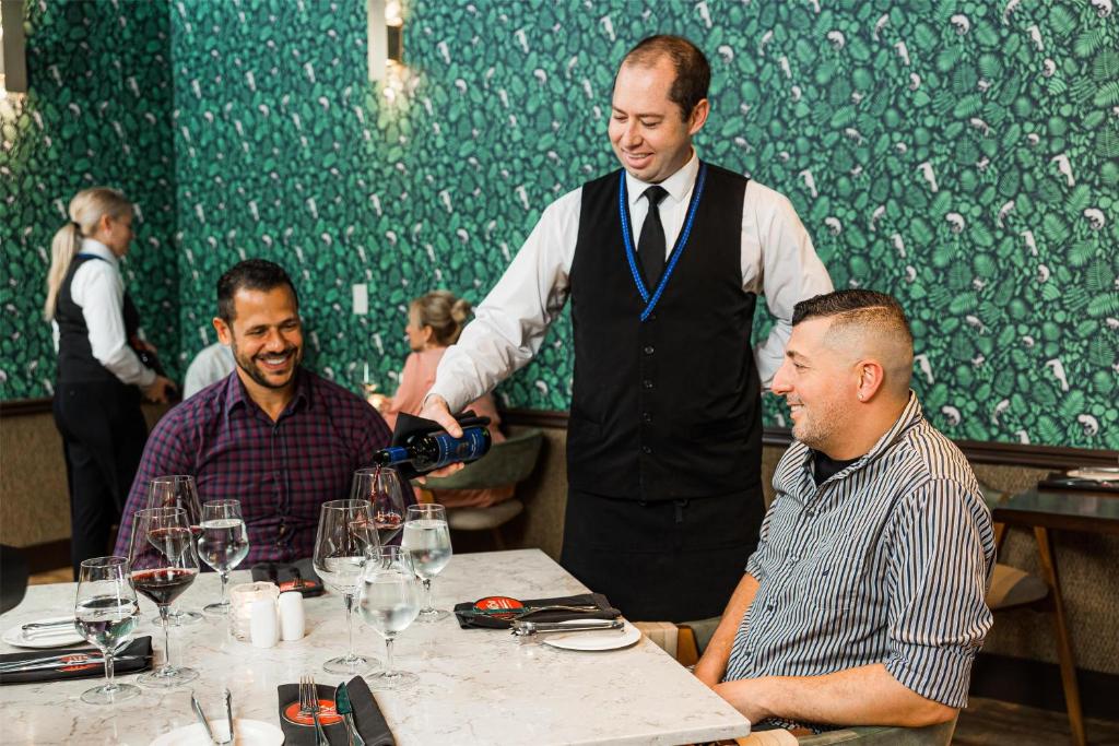 a man is pouring a glass of wine in a restaurant at Hilton Niagara Falls/ Fallsview Hotel and Suites in Niagara Falls