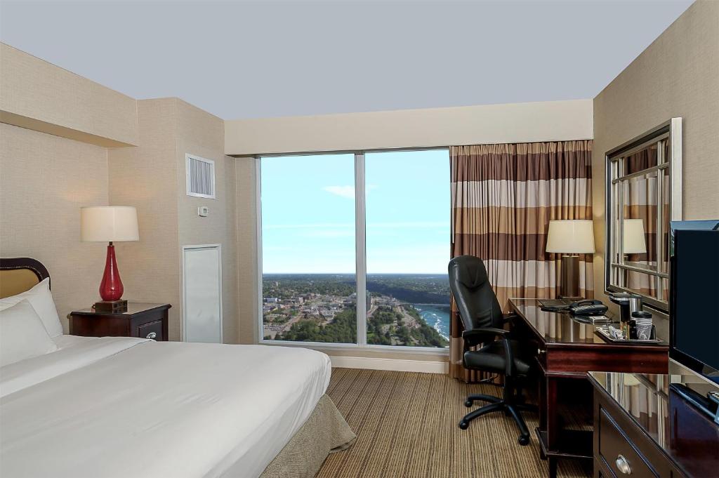 a hotel room with a bed and a desk with a computer at Hilton Niagara Falls/ Fallsview Hotel and Suites in Niagara Falls