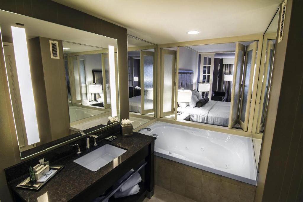 a bathroom with a tub and a bed and mirrors at Hilton Niagara Falls/ Fallsview Hotel and Suites in Niagara Falls