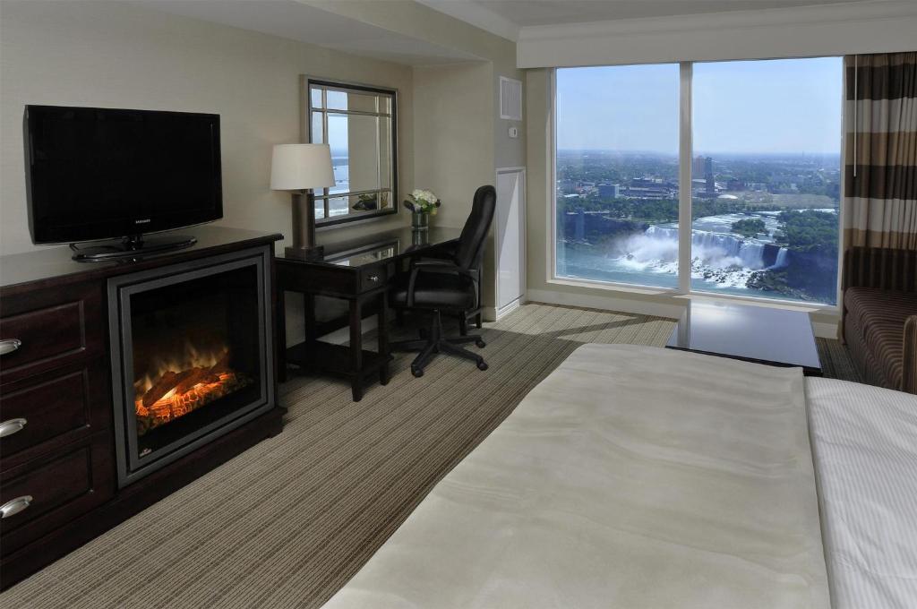 a hotel room with a fireplace and a desk with a television at Hilton Niagara Falls/ Fallsview Hotel and Suites in Niagara Falls