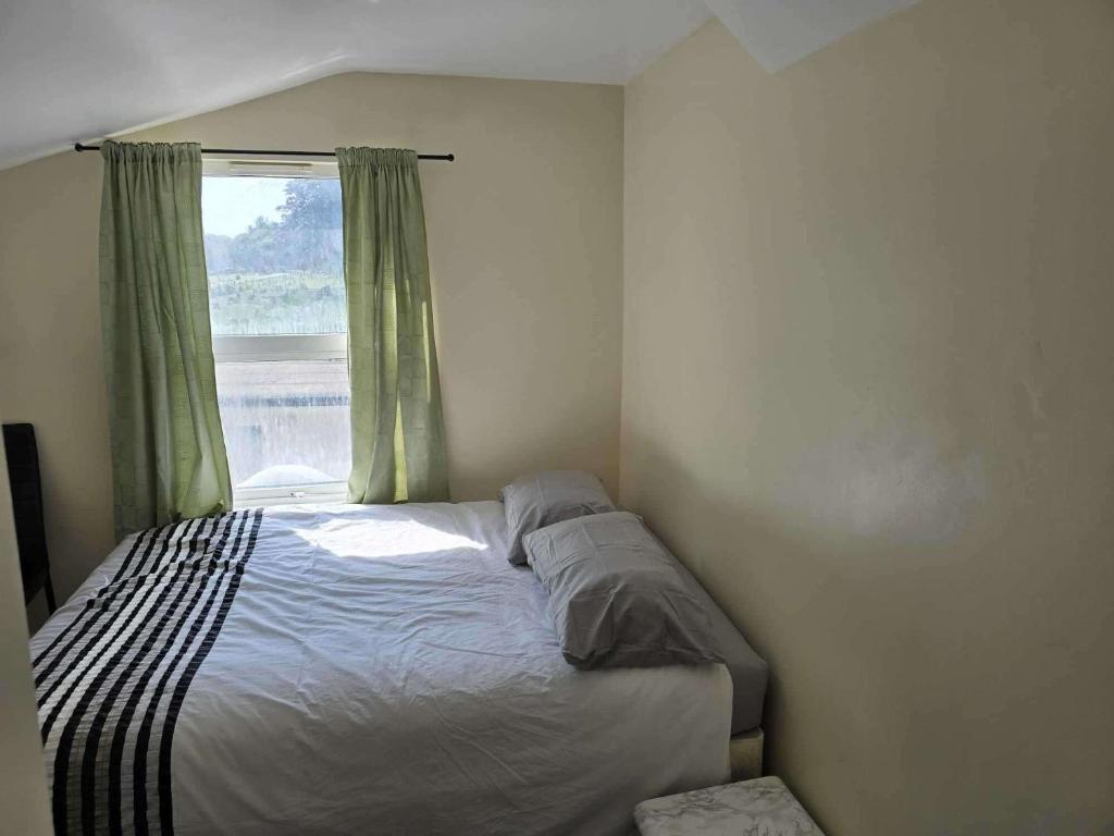 una cama en un dormitorio con ventana en House - Sleeps 8 - Garden - Short Walk to Station, en Londres