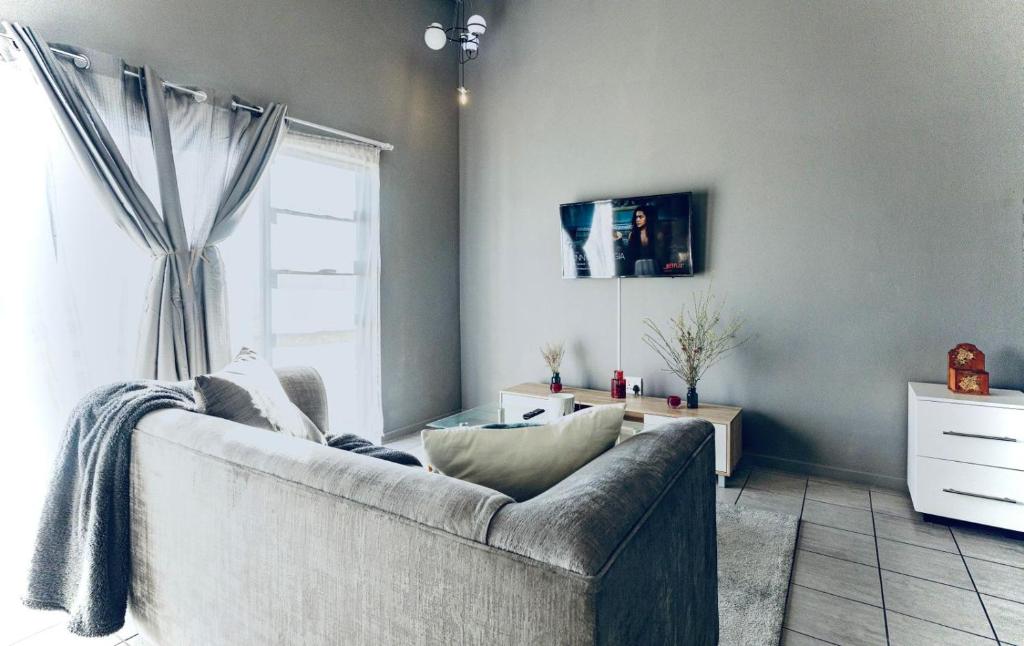 Una sala de estar con un sofá y una ventana. en Dainfern Fourways apartment offering privacy and a lavishly expansive balcony views, en Sandton