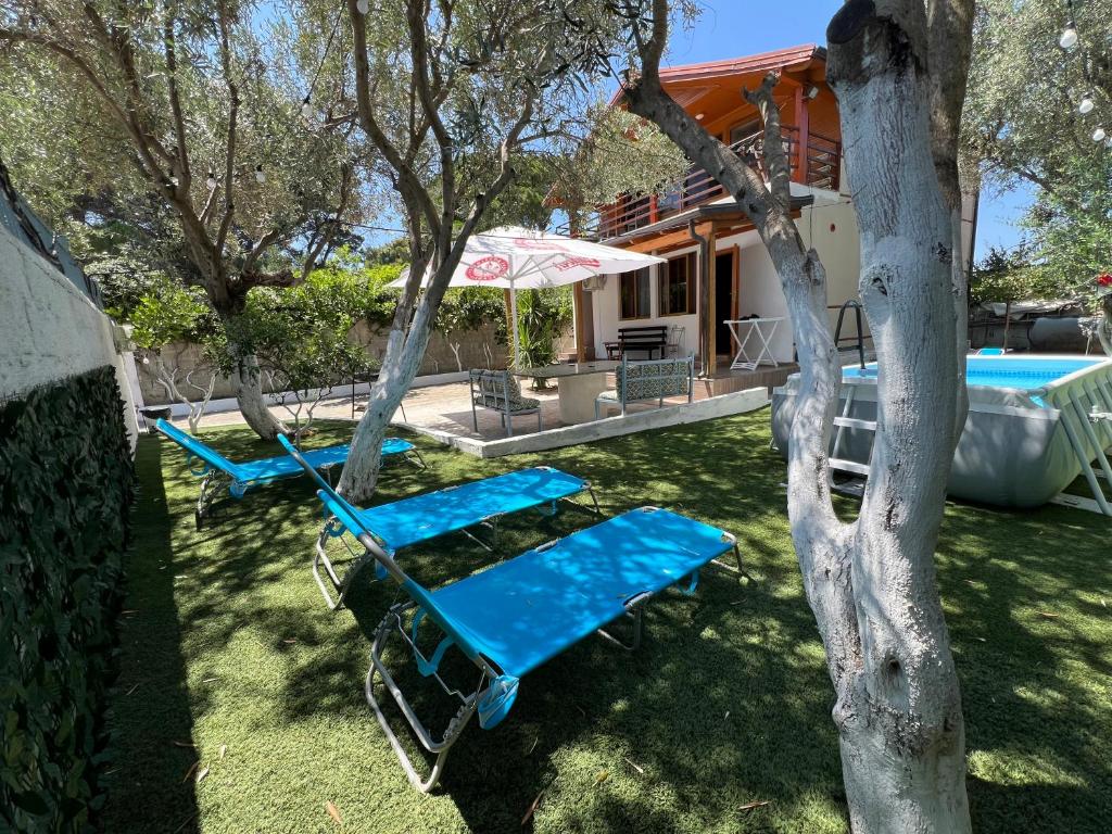 a yard with two blue lounge chairs and a house at Mone luxury villa in Vlorë