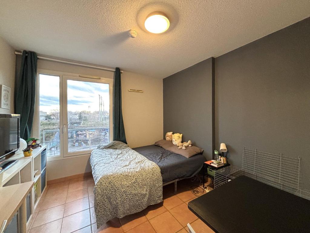 une chambre avec un lit et une grande fenêtre dans l'établissement Studio 2 pers proche rempart, à Avignon