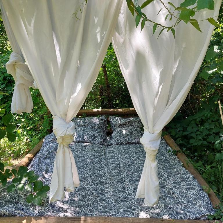 un rideau blanc sur une allée en pierre dans l'établissement Insolite - Nuit à la belle étoile dans gazébo thaï près de la rivière, à Les Plantiers