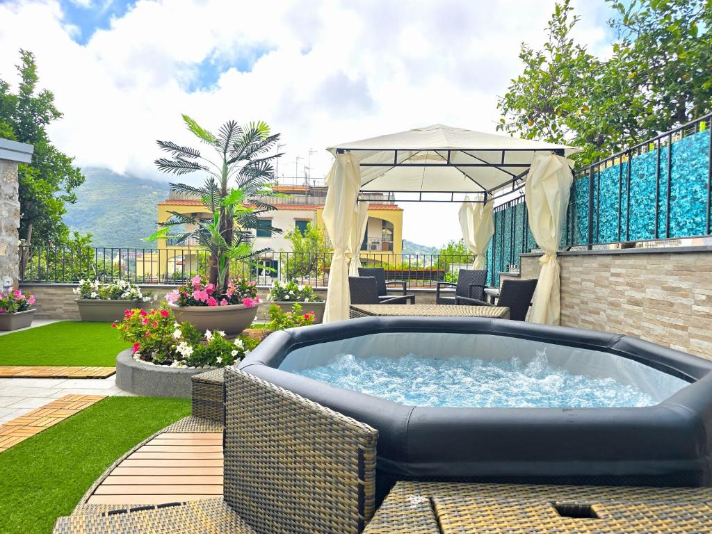 a hot tub on a patio with an umbrella at Grazy Home - Bright new Apt with Terrace and Seasonal Pool in Vico Equense