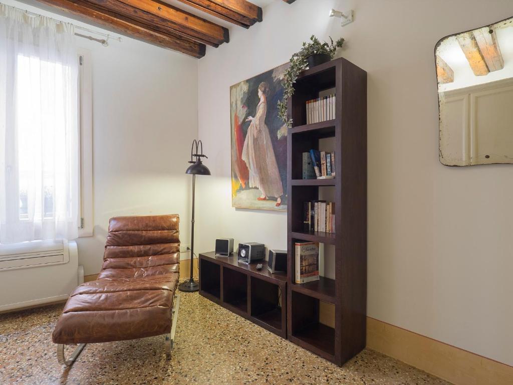 a living room with a chair and a book shelf at Casa Margherita in Venice