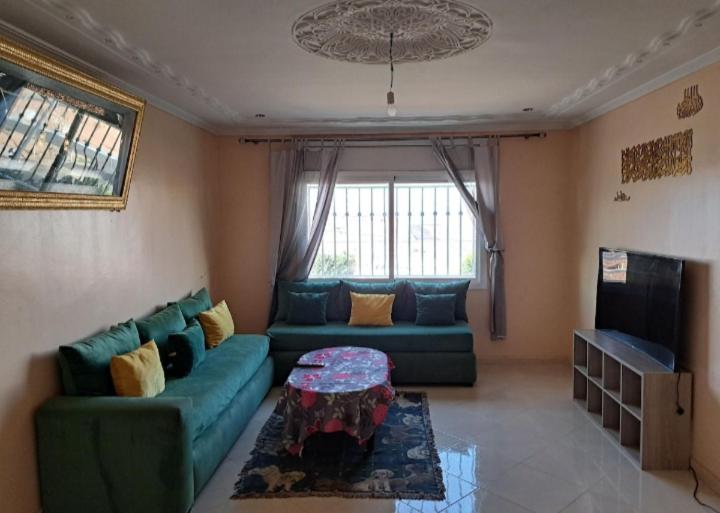 a living room with a green couch and a table at دار الضيافة سلوان ليلى in Selouane