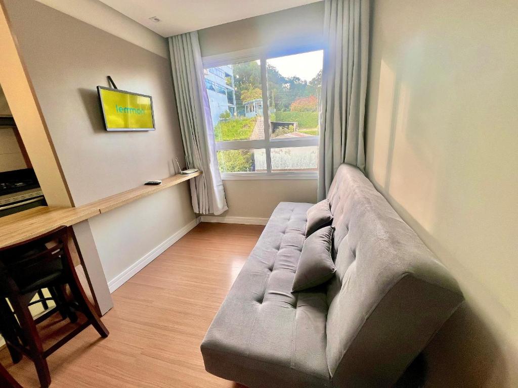 a couch in a living room with a window at Urban Apt 601 Comfortable and Complete in Caxias do Sul