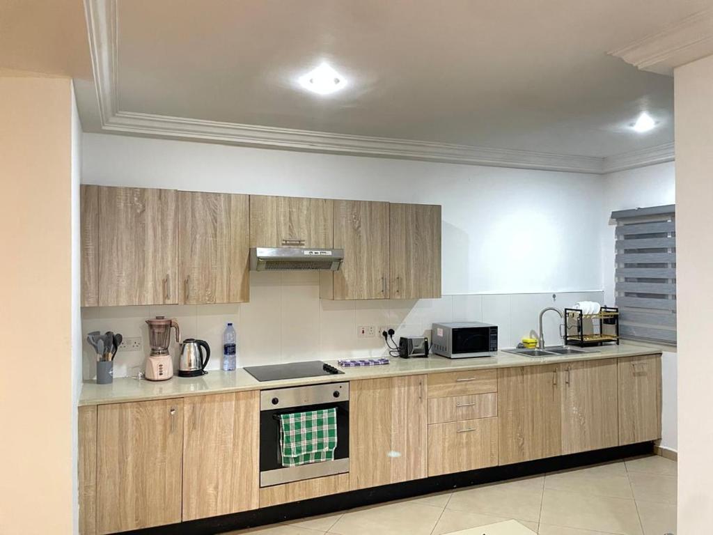 a kitchen with wooden cabinets and a stove top oven at Sunny's Place Luxury Apartments in Accra