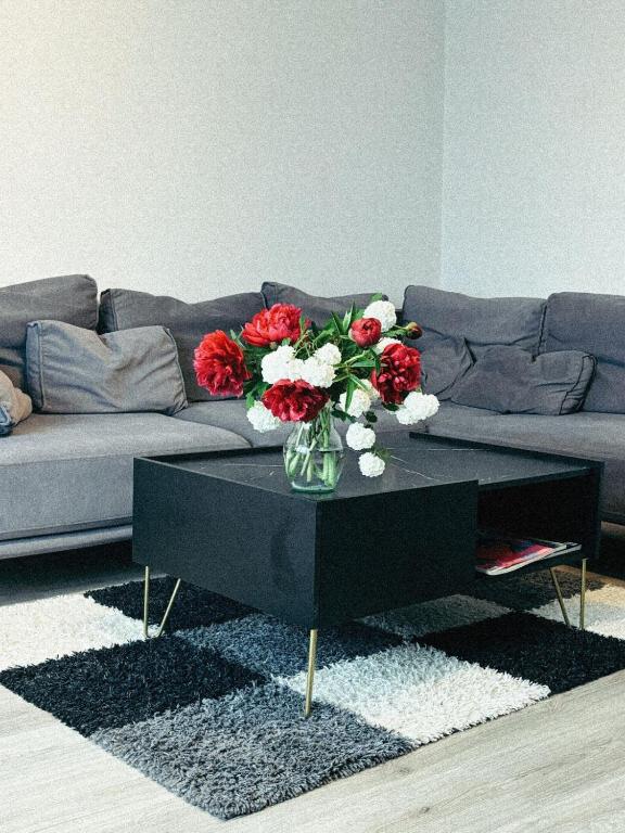 a black coffee table with a vase of red and white flowers at Mērsraga Miera Osta in Mērsrags
