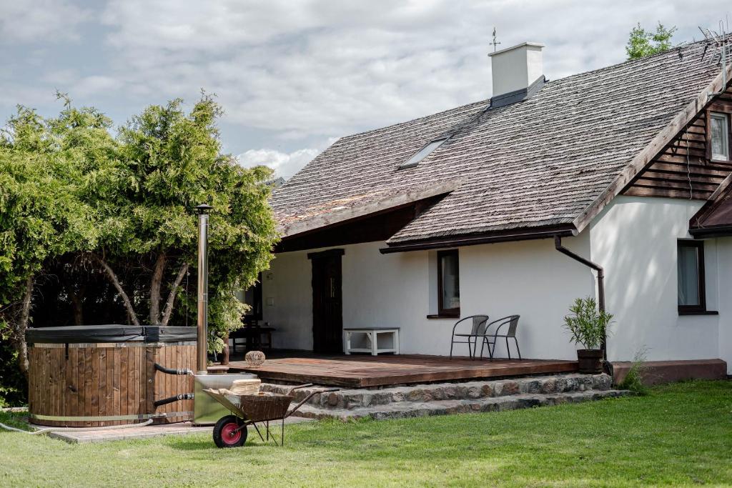 a white house with a wooden deck in the yard at Dom Góra na Mazurach Balia z jacuzzi in Góra