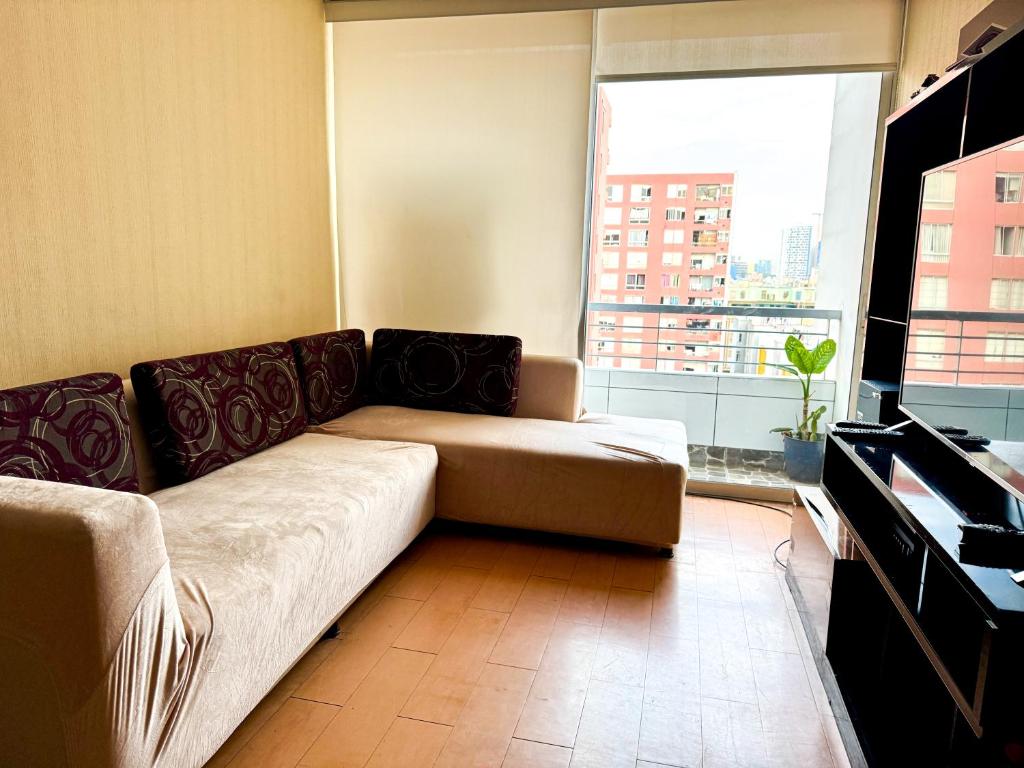 a living room with a couch and a large window at Departamento centrico, moderno, excelente ubicacion en Breña in Lima